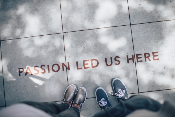 Photo of two people's feet on a sidewalk that says "Passion led us here"